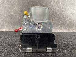 Automotive ABS brake pump module with silver metal housing and a black base.