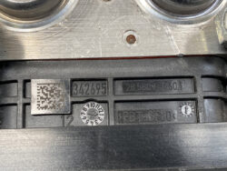 Close-up of an automotive identification plate with serial numbers, a QR code, and a circular 12-position dial (numbers 1–12).