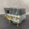 ABS brake module with yellow protective caps on its ports resting on a dark work surface. Nissan Atlas Genuine ABS Actuator Pump 47660-MA00A / 06 2102-1015 » JDM-PARTS NZ