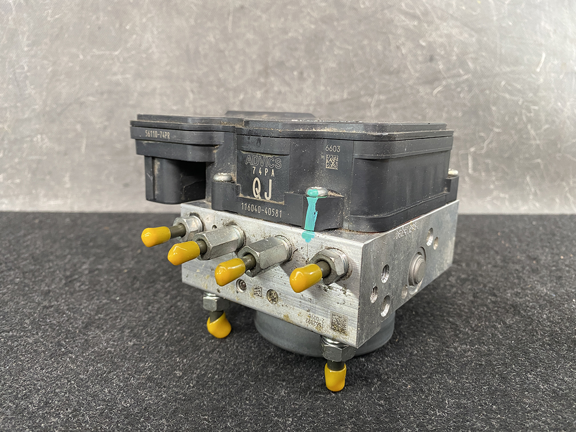 SUZ-ACTR-74PR _2 Suzuki Alto Genuine ABS Actuator Pump / 56110-74PR / 116040-40581 » NZ9.95 » JDM-PARTS NZ » JDM-PARTS NZ ABS brake module with yellow protective caps on its ports resting on a dark work surface. Suzuki Alto Genuine ABS Actuator Pump / 56110-74PR / 116040-40581 » JDM-PARTS NZ
