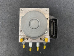 Automotive ABS brake pump module with a gray circular actuator, aluminum housing, and a multi-pin connector on the right side.