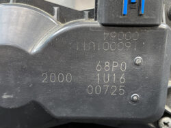 Close-up of a black plastic component with stamped numbers (e.g., 2000, 68P0, 1U16, 00725) and two small screws, plus a blue toggle on top left.