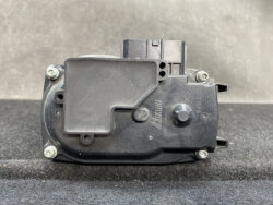 Automotive door lock actuator module with visible bolts and molded plastic housing, branded NIKUNI.