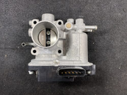 Electronic throttle body with intake bore and multi-pin electrical connector at the base.