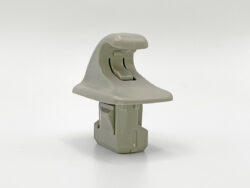 Gray plastic model part with a curved top and clamp-like slot, mounted on a rectangular base.