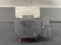 Electrical control/actuator module: black octagonal housing with a metal mounting block on top and two multi-pin connectors on the right side, dusty and worn.