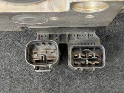 Close-up of an automotive control unit showing two rectangular multi-pin electrical connectors side by side on a black housing.