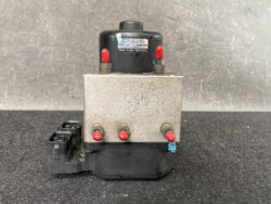 Metal hydraulic control unit with four red-tipped ports and a black connector, likely an automotive brake modulator component.