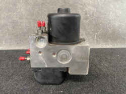 Industrial hydraulic valve block with red terminal posts, a black solenoid coil, and a front round gauge port on a metal housing.
