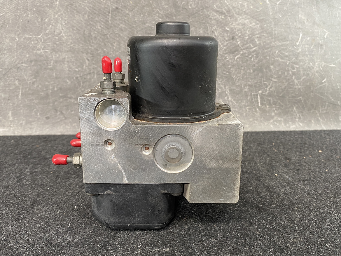 TOY-ACTR-24060_6 Toyota Chaser Altezza Genuine ABS Actuator Pump 44510-24060 / 133000-5050 » NZ9.95 » JDM-PARTS NZ » JDM-PARTS NZ Industrial hydraulic valve block with red terminal posts, a black solenoid coil, and a front round gauge port on a metal housing. Toyota Chaser Altezza Genuine ABS Actuator Pump 44510-24060 / 133000-5050 » JDM-PARTS NZ