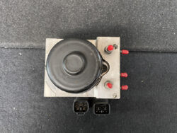 Electrical control module with a round black component on top, red terminal posts on the right, and two multi-pin connectors at the bottom.