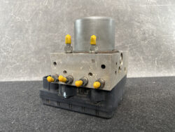 Metal hydraulic valve manifold with yellow capped ports mounted on a black base, showing multiple screws and passing holes
