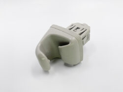 Close-up of a gray plastic component with a curved, finger-like hollow grip attached to a rectangular, vented connector.