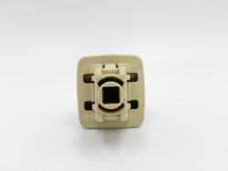Close-up of a beige plastic electrical switch/module facing the camera, showing a central circular receptacle and mounting frame
