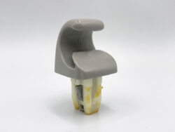 Gray plastic interior trim clip with a curved top, mounted on a yellowish base used to secure panels in a vehicle