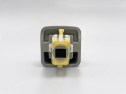 Front view of a gray plastic connector housing with yellow latch tips and a central square opening, seen from the front.