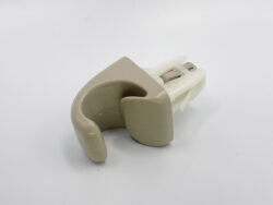 Beige curved ear-prosthesis component attached to a white plastic connector.