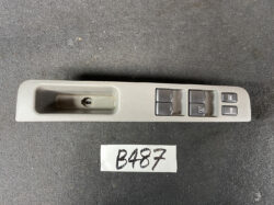 Gray car door panel with a recessed handle and four window control switches plus lock buttons on the right side