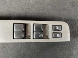 Driver-side car door panel with four power window switches and two small function buttons (window lock and rear window lock)