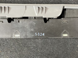 Close-up of a dark plastic mounting with the number 5324 stamped in light blue, and two small translucent indicator windows on each side under a gray housing.