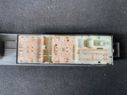 Internal view of a disassembled car switch/module showing orange copper circuit traces on pale plastic. On the right are connector areas and slots for mating parts.