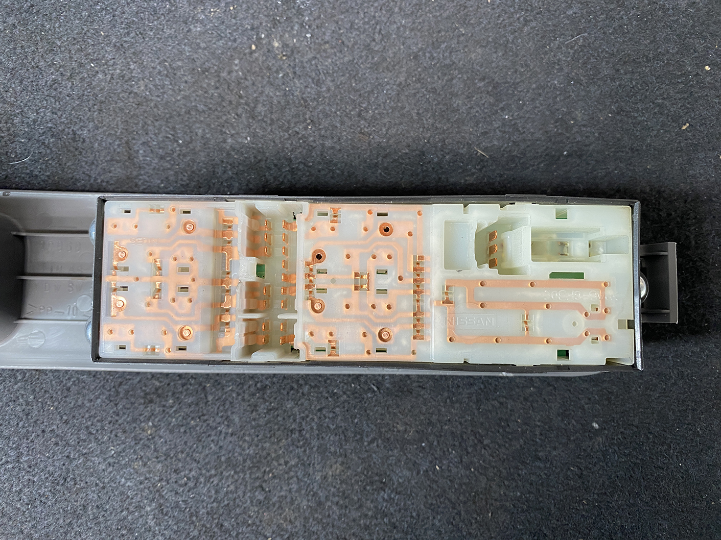 B487_6 NISSAN CUBE Z11 Genuine Master Power Window Switch 80960 3U000 » NZ.95 » JDM-PARTS NZ » JDM-PARTS NZ Internal view of a disassembled car switch/module showing orange copper circuit traces on pale plastic. On the right are connector areas and slots for mating parts. NISSAN CUBE Z11 Genuine Master Power Window Switch 80960 3U000 » JDM-PARTS NZ
