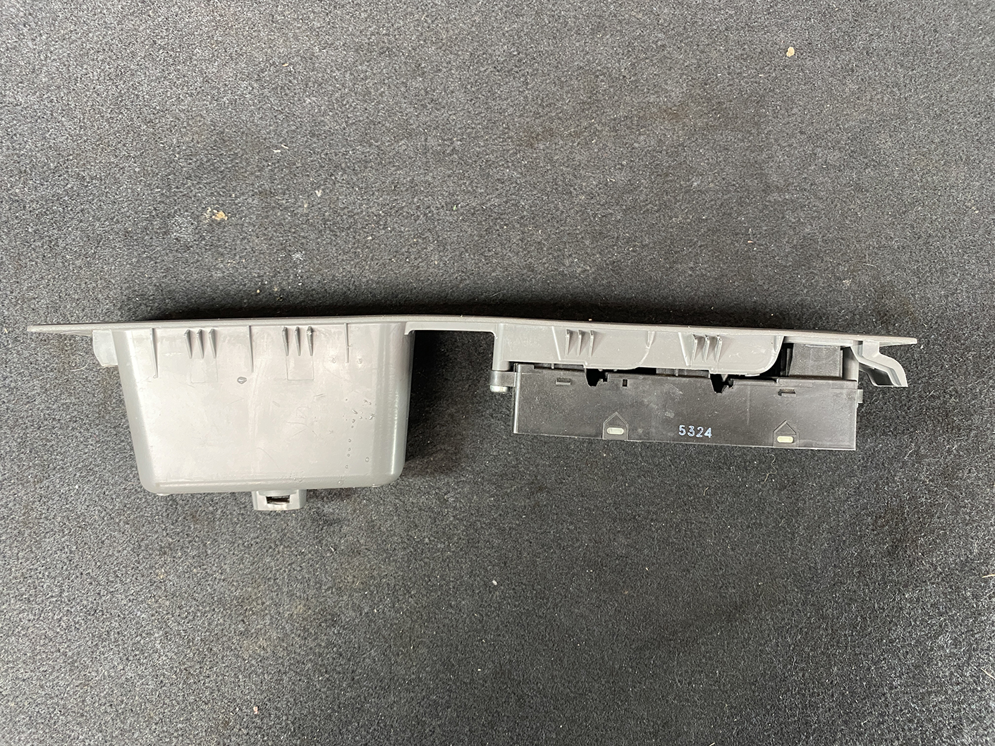 B487_8 NISSAN CUBE Z11 Genuine Master Power Window Switch 80960 3U000 » NZ.95 » JDM-PARTS NZ » JDM-PARTS NZ Gray two-piece automotive component with a long plastic housing and a black connector block on a dark carpet surface. NISSAN CUBE Z11 Genuine Master Power Window Switch 80960 3U000 » JDM-PARTS NZ