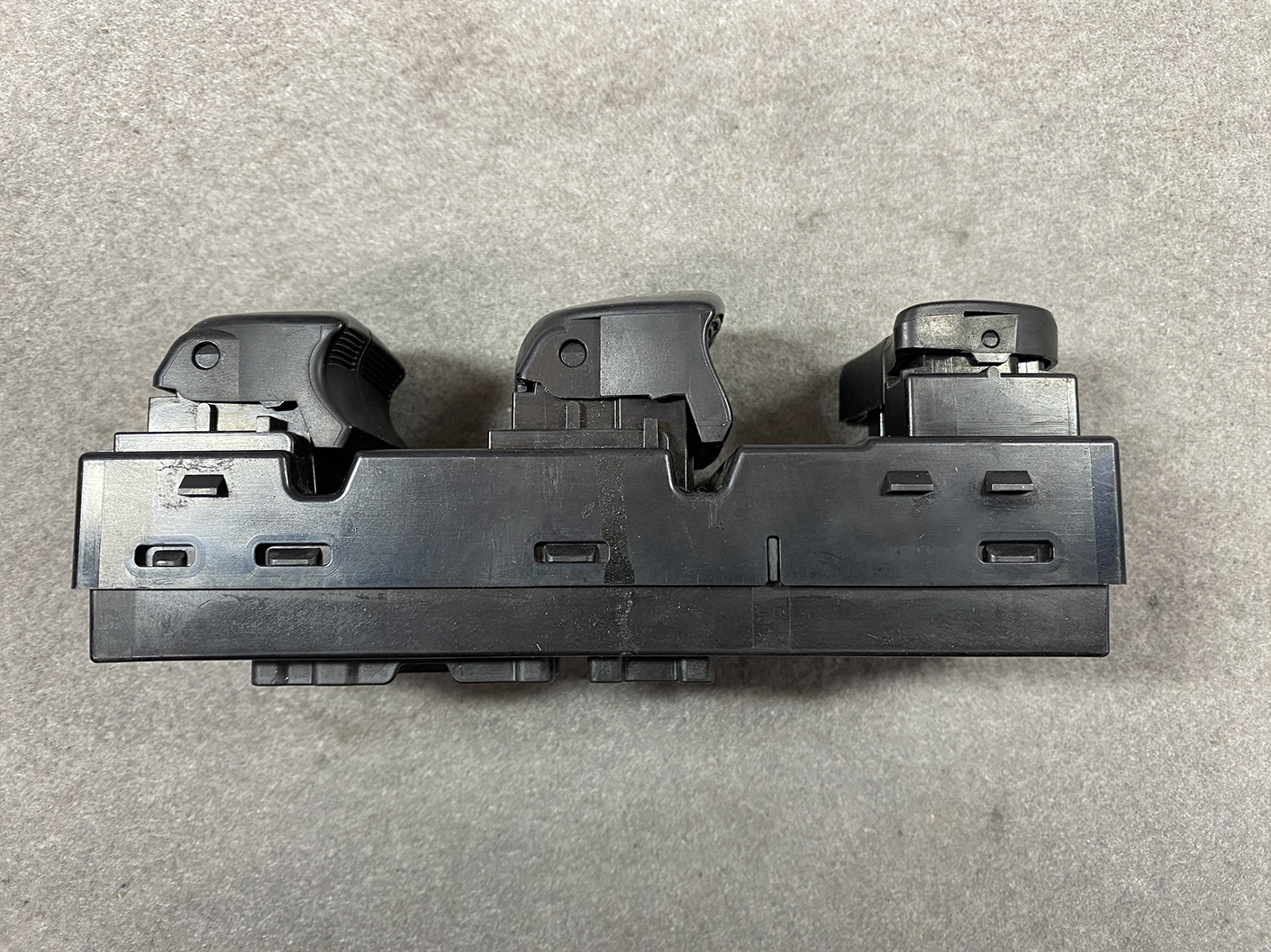 B488_7 NISSAN SERENA SUZUKI LANDY C26 Genuine Master Power Window Switch 25401 1VA7A » NZ.95 » JDM-PARTS NZ » JDM-PARTS NZ Black plastic car switch assembly with three toggle levers on a rectangular base, laid on a gray surface. NISSAN SERENA SUZUKI LANDY C26 Genuine Master Power Window Switch 25401 1VA7A » JDM-PARTS NZ