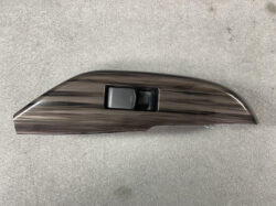 Dark wood-grain car interior trim with a central window switch panel.