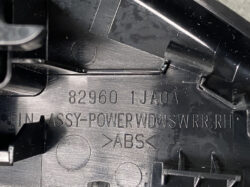Close-up of a black ABS automotive interior part showing part number 82960 1JA0A and RH (right-hand) designation with molded text pieces nearby.