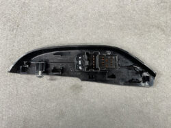Black plastic car side mirror housing showing the electrical connector and mounting area, photographed on a gray surface.