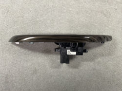 Dark brown metallic car door handle with black plastic mounting bracket and label on the base, shown from the side