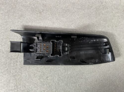 Nissan door switch panel with a multi-pin electrical connector mounted on black plastic.