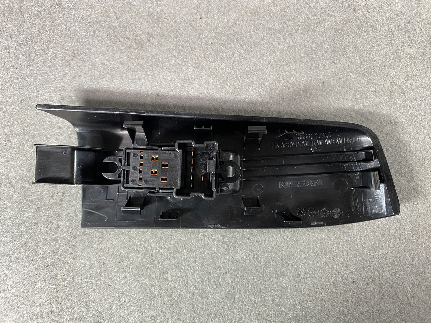 B491_6 NISSAN ELGRAND E52 Genuine Front Left Power Window Switch 25411 JD05A » NZ.95 » JDM-PARTS NZ » JDM-PARTS NZ Nissan door switch panel with a multi-pin electrical connector mounted on black plastic. NISSAN ELGRAND E52 Genuine Front Left Power Window Switch 25411 JD05A » JDM-PARTS NZ