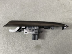 Nissan power window switch panel with wiring connector, black and curved trim piece for a car door interior