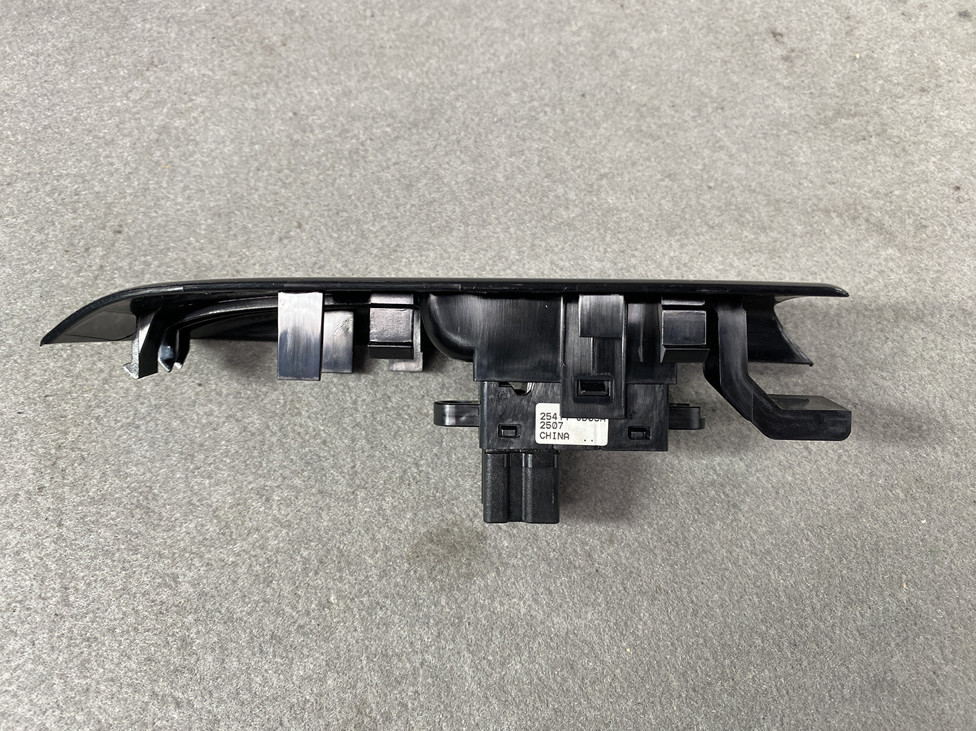 B491_8 NISSAN ELGRAND E52 Genuine Front Left Power Window Switch 25411 JD05A » NZ.95 » JDM-PARTS NZ » JDM-PARTS NZ Black plastic automotive switch assembly with multiple mounting clips and a central electrical connector, likely a car door/window control module NISSAN ELGRAND E52 Genuine Front Left Power Window Switch 25411 JD05A » JDM-PARTS NZ