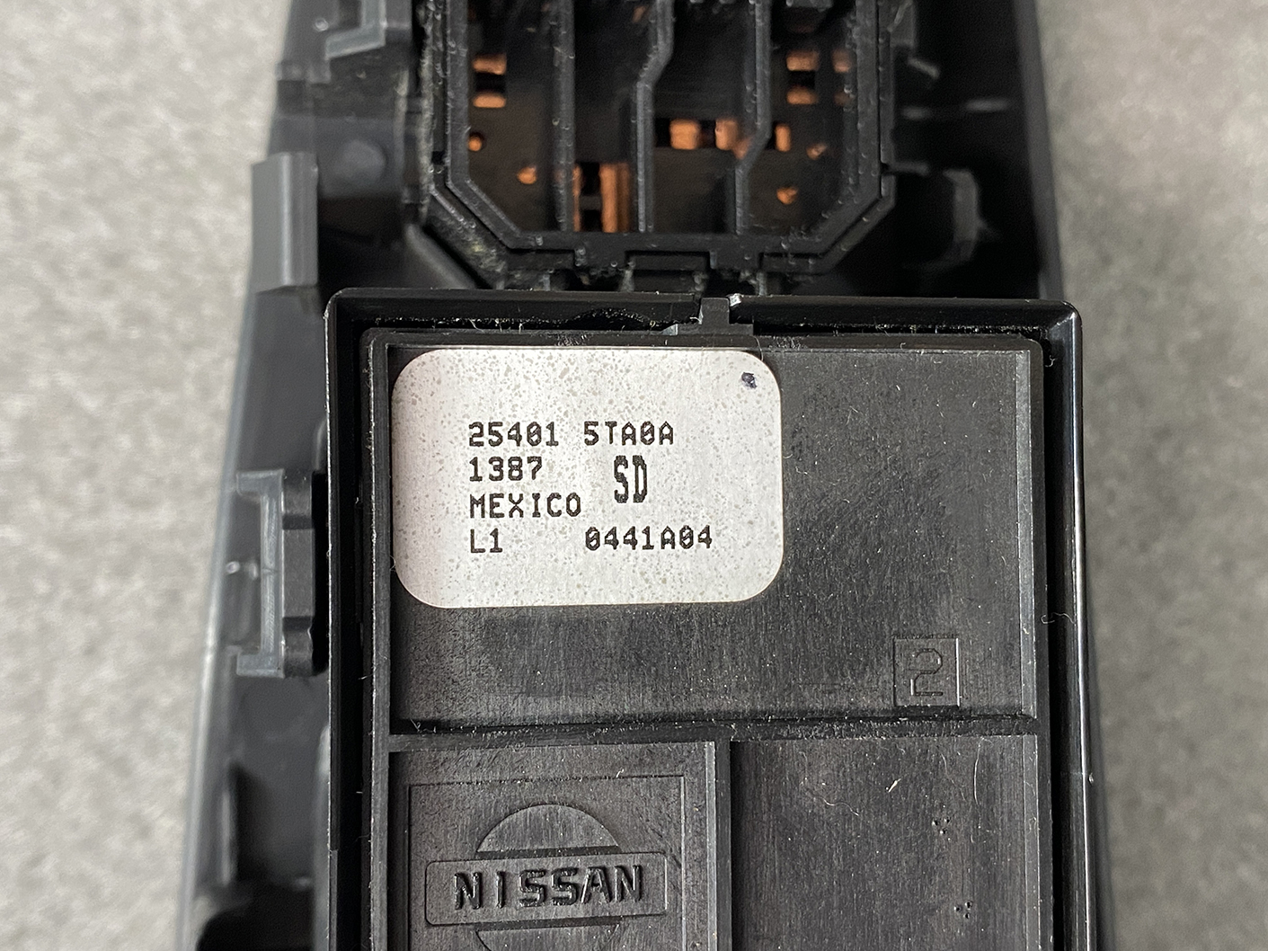 B492_5 NISSAN SERENA SUZUKI LANDY C27 Master Power Window Switch 25401 5TA0A » NZ1.95 » JDM-PARTS NZ » JDM-PARTS NZ Close-up of a Nissan electrical module with a white label showing part numbers and 'MEXICO' text, Nissan logo below. NISSAN SERENA SUZUKI LANDY C27 Master Power Window Switch 25401 5TA0A » JDM-PARTS NZ