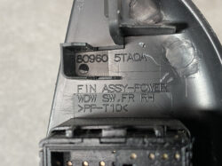 Close-up of a black automotive power assembly housing with embossed part numbers and a multi-pin connector visible at the bottom.