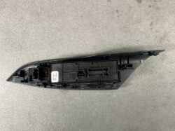 Black plastic car side-view mirror housing with exposed electrical connectors on a gray surface.