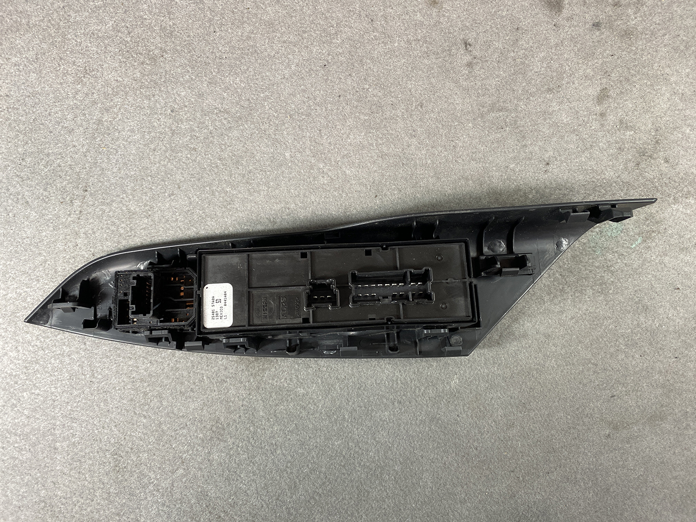 B492_8 NISSAN SERENA SUZUKI LANDY C27 Master Power Window Switch 25401 5TA0A » NZ1.95 » JDM-PARTS NZ » JDM-PARTS NZ Black plastic car side-view mirror housing with exposed electrical connectors on a gray surface. NISSAN SERENA SUZUKI LANDY C27 Master Power Window Switch 25401 5TA0A » JDM-PARTS NZ