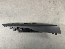 Black plastic car door window switch panel with multiple buttons and mounting clips, viewed from the side