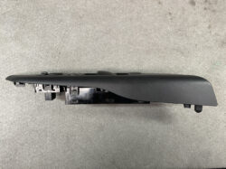 Black automotive door switch panel with exposed wiring/connectors on the left, likely a power window/lock module awaiting installation or removal.