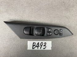 Car door control panel: four power window switches, door lock buttons, and a circular mirror-adjustment joystick on a black curved armrest piece.