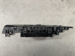 Black plastic car window switch panel (power window control) viewed from side, showing multiple button slots and housings.