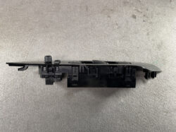 Black automotive dashboard switch panel with knobs and multiple connectors on a gray surface, likely a control module for vehicle functions.