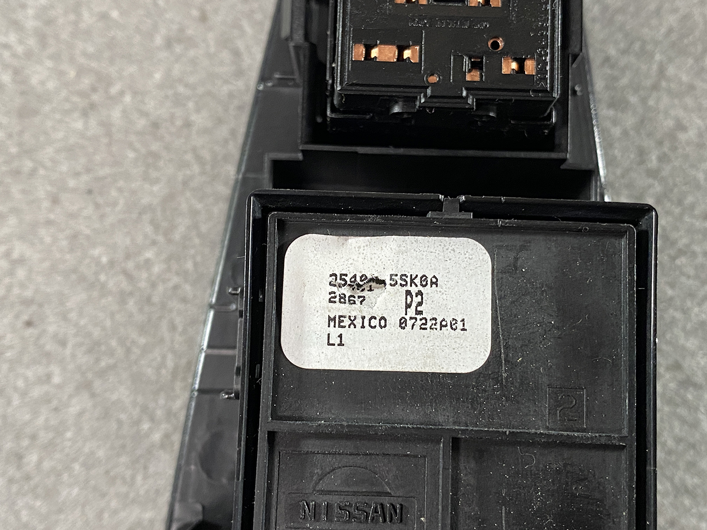 B494_4 NISSAN NOTE E11 Genuine Master Power Window Switch 25401 5SK0A » NZ.95 » JDM-PARTS NZ » JDM-PARTS NZ Close-up of a Nissan automotive control module with a white label showing part codes and 'Mexico' origin. NISSAN NOTE E11 Genuine Master Power Window Switch 25401 5SK0A » JDM-PARTS NZ