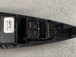 Close-up of a black automotive electrical connector with copper pins and a white label on the side.