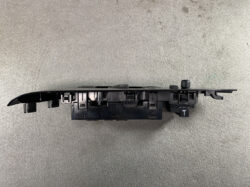 Black plastic automotive switch panel with multiple mounting clips, likely a control module from a car door or dash