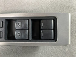 Close-up of power window switch panel on a car door in a gray frame with four black buttons