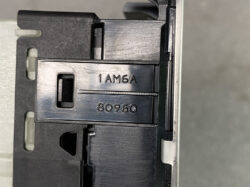 Close-up of a metallic cartridge/slide with the engraved numbers 1 AM6A and 80960, set in a dark plastic housing.